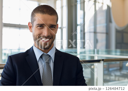 Businessman in suit smiling confidently in modern conference center lobby, copy space Businessman in suit smiling confidently in modern conference center lobby, copy space 126484712