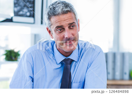 Confident businessman in blue shirt listening attentively in modern office Confident businessman in blue shirt listening attentively in modern office 126484898