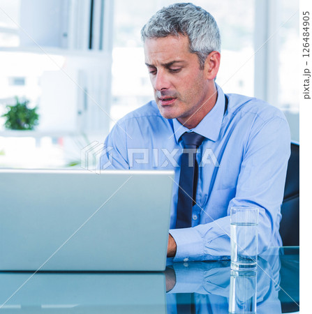In office, businessman working on laptop, focused and professional at desk 126484905