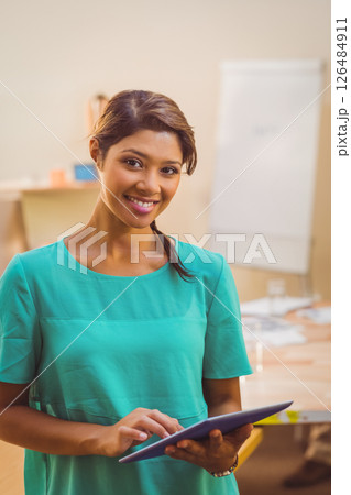 Smiling woman using tablet in modern office, engaging in casual business tasks Smiling woman using tablet in modern office, engaging in casual business tasks 126484911