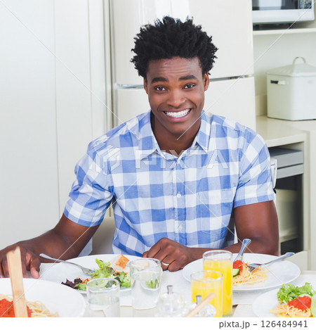 Smiling man enjoying meal at home with fresh salad and juice Smiling man enjoying meal at home with fresh salad and juice 126484941