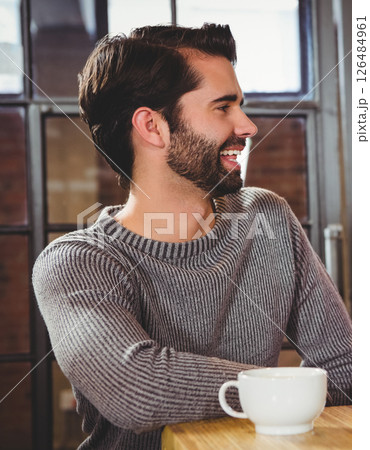 Smiling man enjoying coffee in cozy cafe, wearing stylish sweater Smiling man enjoying coffee in cozy cafe, wearing stylish sweater 126484961