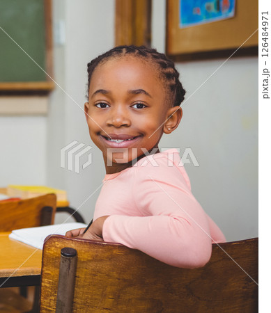 Smiling girl sitting in classroom, looking back at camera, feeling happy 126484971