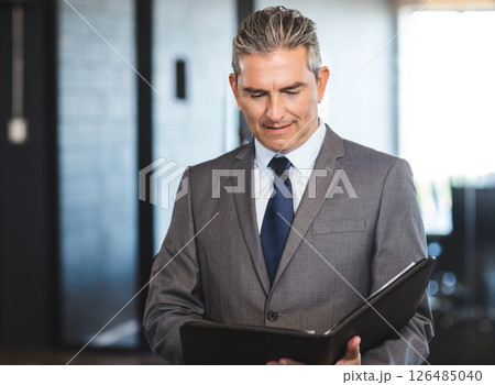 Businessman reviewing documents in office hallway, focusing on important details 126485040