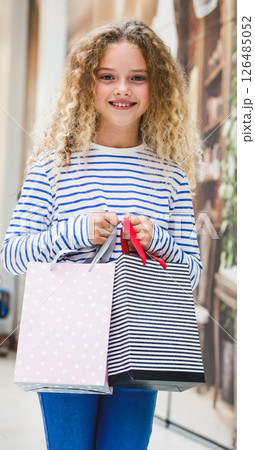 Smiling girl holding shopping bags in mall, enjoying successful shopping day 126485052