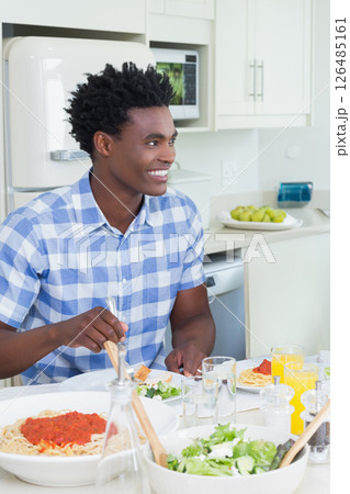 Smiling man enjoying pasta meal in bright kitchen, feeling happy and relaxed Smiling man enjoying pasta meal in bright kitchen, feeling happy and relaxed 126485161