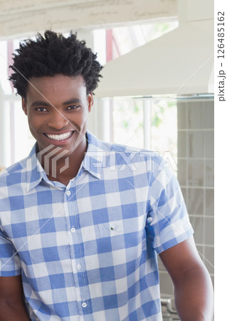 Smiling African American man in kitchen wearing blue checkered shirt 126485162