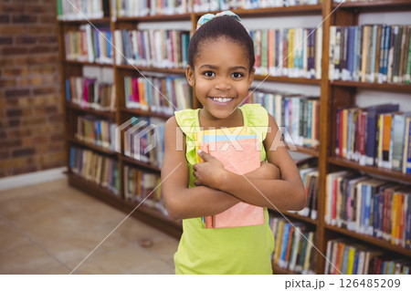 Smiling African American girl holding books in school library, feeling happy 126485209
