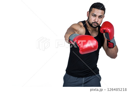 Boxer in red gloves throwing punch, focused and determined in studio, copy space Boxer in red gloves throwing punch, focused and determined in studio, copy space 126485218