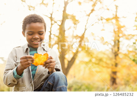 Smiling boy holding autumn leaf in park, enjoying nature's beauty, copy space 126485232