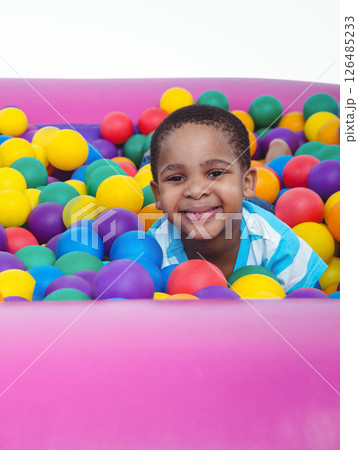 Smiling African American boy playing in colorful ball pit, enjoying fun time Smiling African American boy playing in colorful ball pit, enjoying fun time 126485233