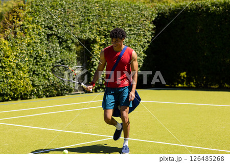 Young man playing tennis on court, smiling and enjoying sunny day outdoors, copy space 126485268