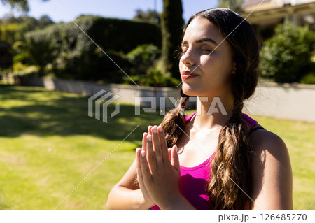 Young woman meditating outdoors, enjoying peaceful moment in sunny garden, copy space 126485270