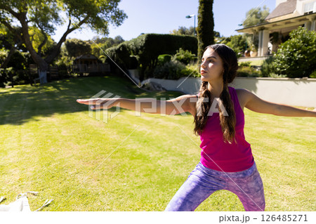 Young woman practicing yoga in backyard, focusing on balance and relaxation, copy space Young woman practicing yoga in backyard, focusing on balance and relaxation, copy space 126485271