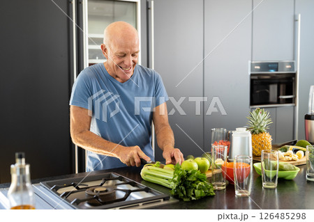 Smiling elderly man preparing healthy meal with fresh vegetables in modern kitchen, copy space Smiling elderly man preparing healthy meal with fresh vegetables in modern kitchen, copy space 126485298