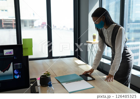 Businesswoman in mask organizing documents and smartphone at modern office desk, copy space Businesswoman in mask organizing documents and smartphone at modern office desk, copy space 126485325