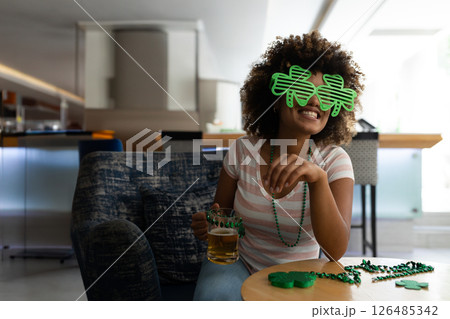 Woman wearing shamrock glasses enjoying beer and laughing at home party, copy space Woman wearing shamrock glasses enjoying beer and laughing at home party, copy space 126485342