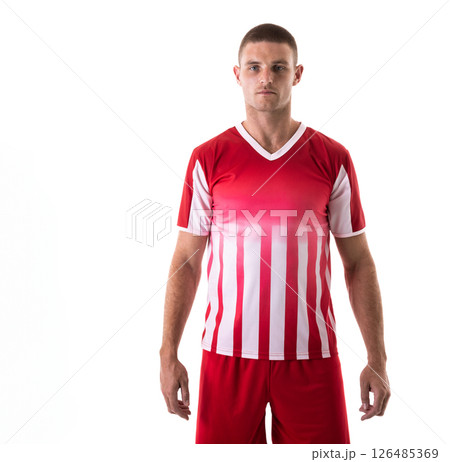 In red and white uniform, male soccer player standing confidently against background, copy space In red and white uniform, male soccer player standing confidently against background, copy space 126485369