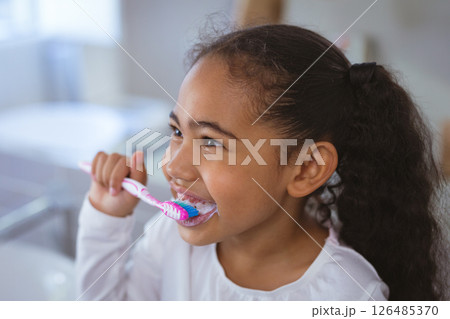 Young girl brushing teeth at home, smiling and enjoying morning routine, copy space 126485370