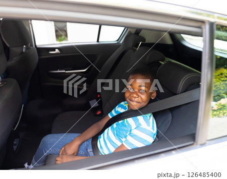 Smiling boy sitting in car backseat, wearing seatbelt, enjoying ride, copy space Smiling boy sitting in car backseat, wearing seatbelt, enjoying ride, copy space 126485400