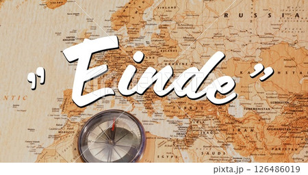 Compass resting on vintage world map with Einde text overlay 126486019