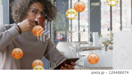 Drinking coffee, young person using smartphone in cafe with virus emojis floating 126486074