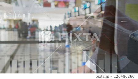 Businessman analyzing financial data on tablet with airport terminal in background Businessman analyzing financial data on tablet with airport terminal in background 126486260