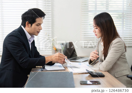 Financial Consultation. Client reviewing documents with a financial advisor in a modern office. Financial Consultation. Client reviewing documents with a financial advisor in a modern office. 126486730