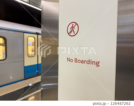 Clear warning sign with red icon and the words No Boarding inside modern subway station, with train stopped nearby. Concept of safety, transportation rules and restricted access area Clear warning sign with red icon and the words No Boarding inside modern subway station, with train stopped nearby. Concept of safety, transportation rules and restricted access area 126487262