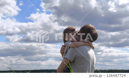 Loving, caring family, happy childhood. Boy in a field in a meadow runs towards brother. family spends time in nature, brothers hug. Brother's Day. little brother runs into the arms of older brother 126487724