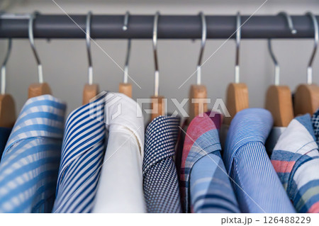 Neatly arranged men shirts hanging on wooden hangers in wardrobe. Minimalist clothing organization and classic male fashion concept 126488229