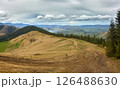 Mountain Trail Through Grassy Hills and Cloudy Sky 126488630