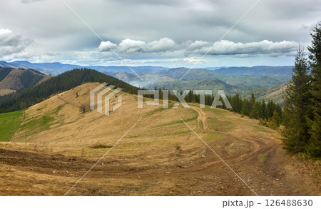 Mountain Trail Through Grassy Hills and Cloudy Sky 126488630