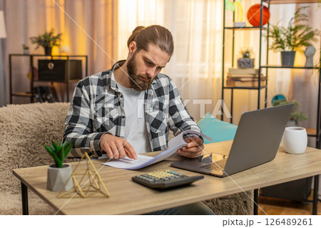 Serious man analyzes contract with a bank at home table clutches head at complex conditions clauses 126489261