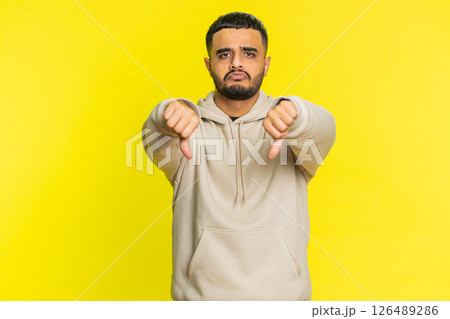 Upset man guy showing thumbs down gesture disapproval dissatisfied dislike negative feedback Upset man guy showing thumbs down gesture disapproval dissatisfied dislike negative feedback 126489286