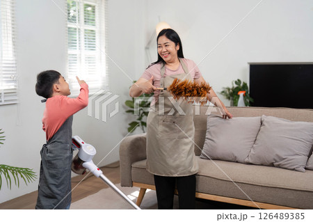 Family Cleaning and Joyful Engagement. A mother and son share a moment while cleaning their living space. Family Cleaning and Joyful Engagement. A mother and son share a moment while cleaning their living space. 126489385