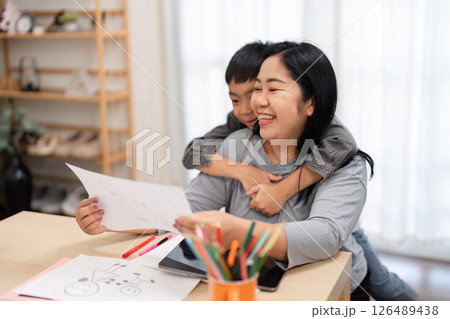 Back to School and Creativity. A mother and son share a loving moment as they review his artwork together. 126489438