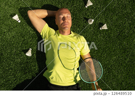 Badminton athlete or player resting after game, lying and enjoy on sport court in public park with artificial turf as green grass. Outdoors. Summer sports game. View from above 126489510