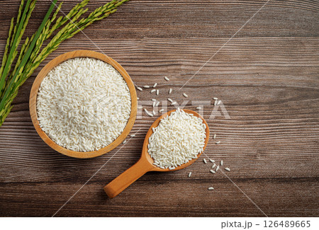 Raw rice in wooden bowl on old wooden table, rice top view. Raw rice in wooden bowl on old wooden table, rice top view. 126489665
