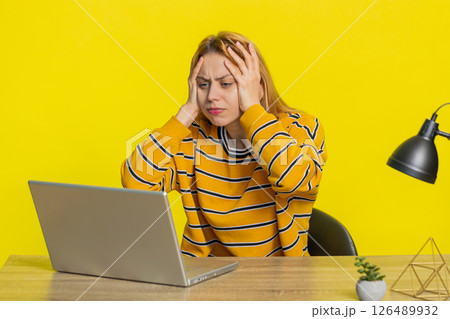 Woman using laptop surprised by bad news, fortune loss, game fail, lottery results sitting at table 126489932