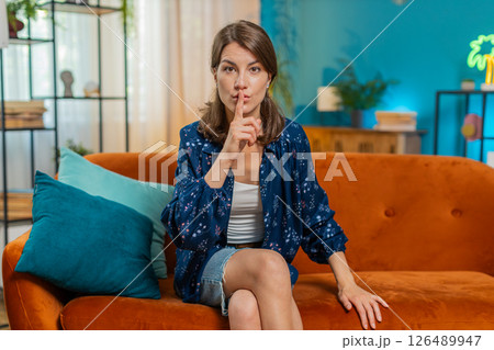 Woman presses index finger to lips makes silence quiet hush gesture sign do not tell gossip secret 126489947