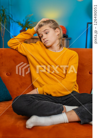 Teenager boy holding head stressed expression thinking deeply after bad day sitting on sofa at home Teenager boy holding head stressed expression thinking deeply after bad day sitting on sofa at home 126490051