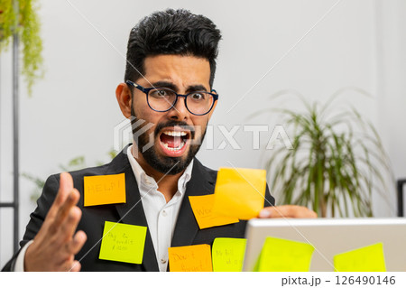 Tired sad exhausted businessman working on laptop at office with many sticker tasks, panic attack Tired sad exhausted businessman working on laptop at office with many sticker tasks, panic attack 126490146