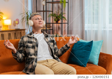 Man listening music, breathes deeply meditating with concentrated thoughts peaceful at home room 126490151