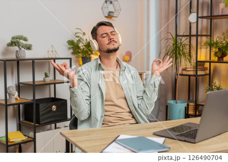 Man listening to music breathes deeply, meditating with concentrated thoughts peaceful mind at table Man listening to music breathes deeply, meditating with concentrated thoughts peaceful mind at table 126490704