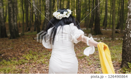 Caucasian middle aged woman in floral wreath running in the forest park looking at camera relaxation Caucasian middle aged woman in floral wreath running in the forest park looking at camera relaxation 126490864