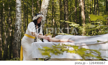 Therapist female doctor making woman relaxing spa face massage with hands outdoors in the forest Therapist female doctor making woman relaxing spa face massage with hands outdoors in the forest 126490867