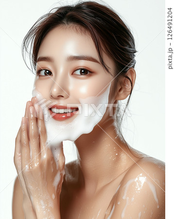 Korean woman enjoying cleansing skincare routine with foam on her face in a bright studio setting 126491204