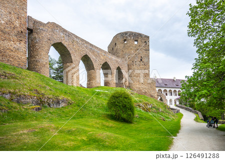 Visitors explore the Gothic Bridge of Velhartice Castle in Czechia, surrounded by lush greenery and historical stone architecture, linking the castle's structures. An atmospheric experience awaits. Visitors explore the Gothic Bridge of Velhartice Castle in Czechia, surrounded by lush greenery and historical stone architecture, linking the castle's structures. An atmospheric experience awaits. 126491288