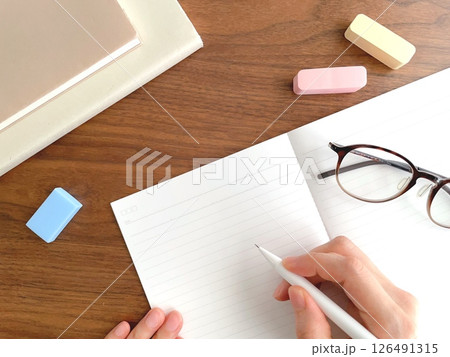 デスクでノートに字を書く女性の手元 デスクでノートに字を書く女性の手元 126491315